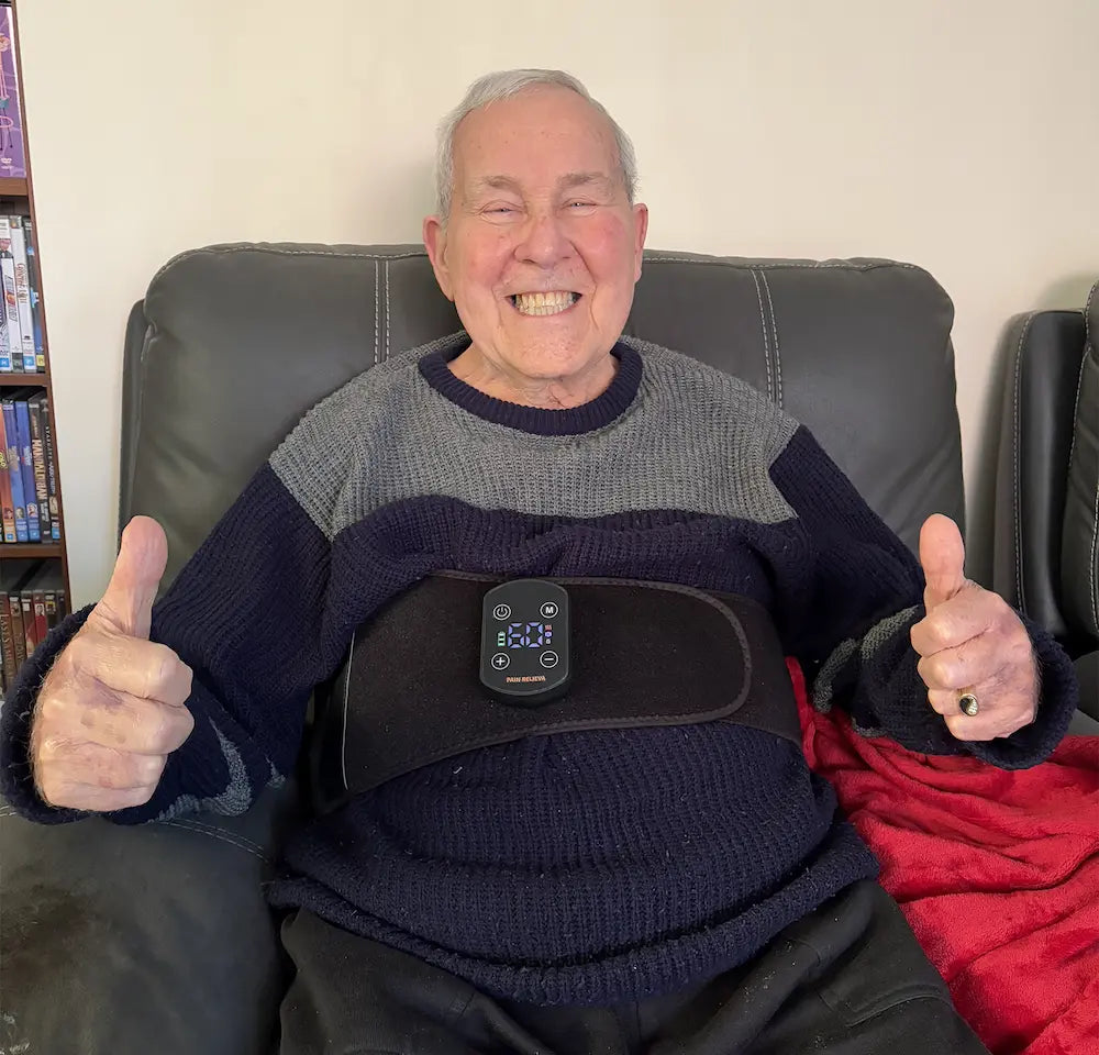 Man sitting on a couch wearing the powered on PainRelieva™ Heated Back Massager, giving a thumbs-up gesture.